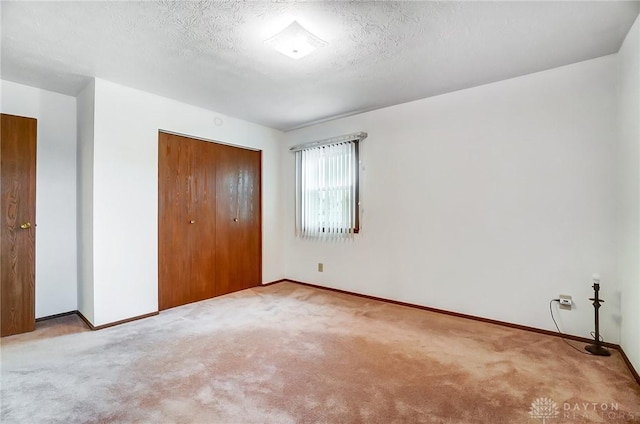 unfurnished bedroom with light colored carpet, a textured ceiling, and a closet