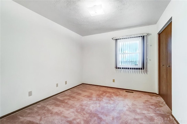 carpeted empty room with a textured ceiling