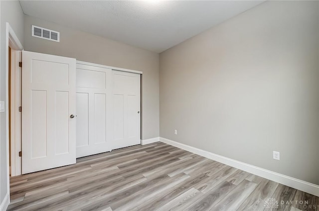 unfurnished bedroom with a closet, a textured ceiling, and light wood-type flooring