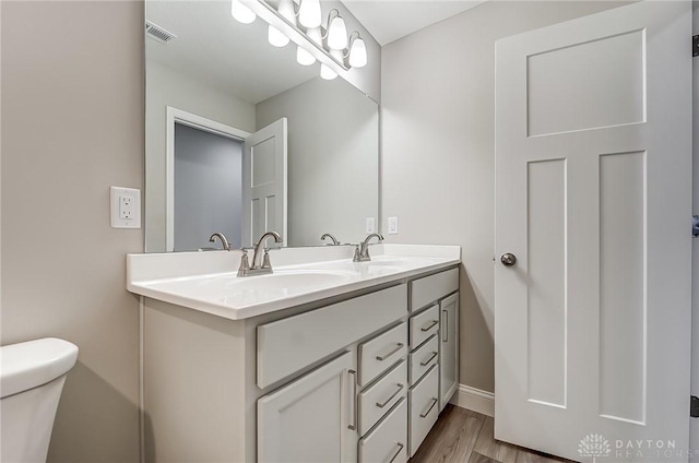 bathroom featuring toilet, vanity, and hardwood / wood-style flooring