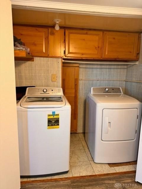 laundry area with washer and dryer, cabinets, and ornamental molding