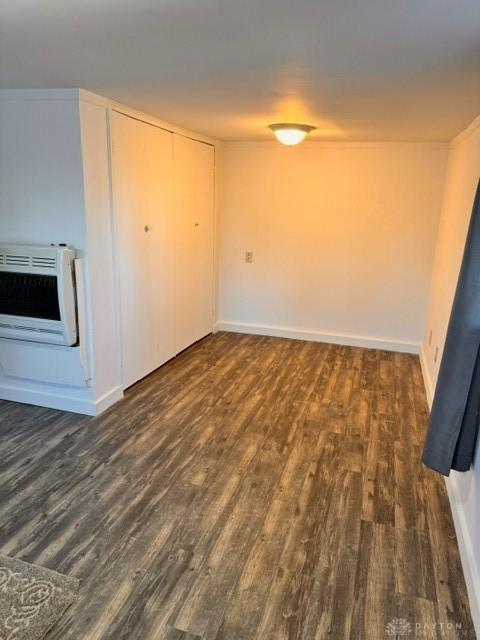 empty room with heating unit and dark wood-type flooring