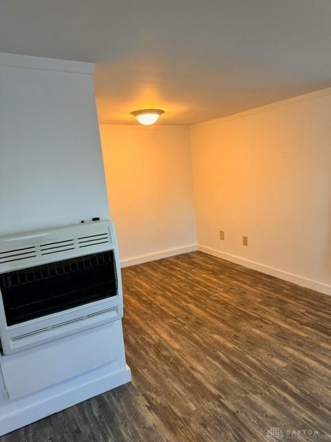 unfurnished room with dark hardwood / wood-style flooring, heating unit, and ornamental molding