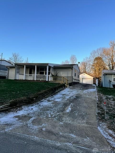 view of front facade featuring an outbuilding, a garage, a front lawn, and covered porch