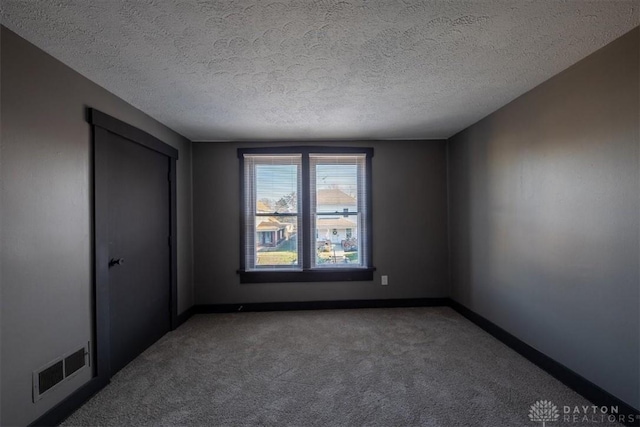 unfurnished room with carpet flooring and a textured ceiling