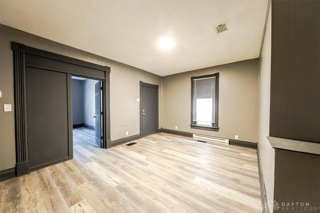 unfurnished room featuring light hardwood / wood-style flooring and wood walls