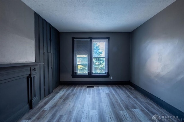 empty room featuring wood-type flooring and a textured ceiling