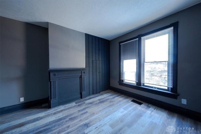 unfurnished living room with hardwood / wood-style floors and a textured ceiling