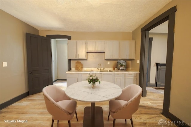 kitchen with light hardwood / wood-style floors, sink, white cabinetry, and a textured ceiling