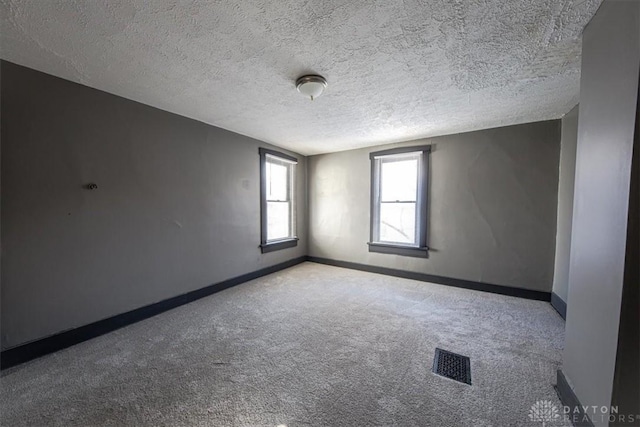 spare room featuring light colored carpet and a textured ceiling