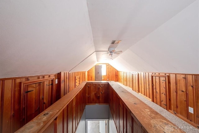 additional living space with carpet, ceiling fan, wood walls, and vaulted ceiling