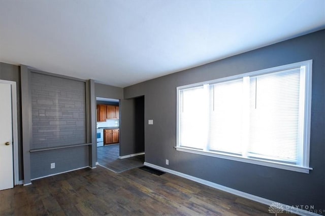 unfurnished room featuring dark hardwood / wood-style floors and a healthy amount of sunlight