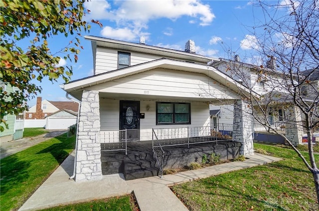 bungalow-style home featuring covered porch and a front lawn