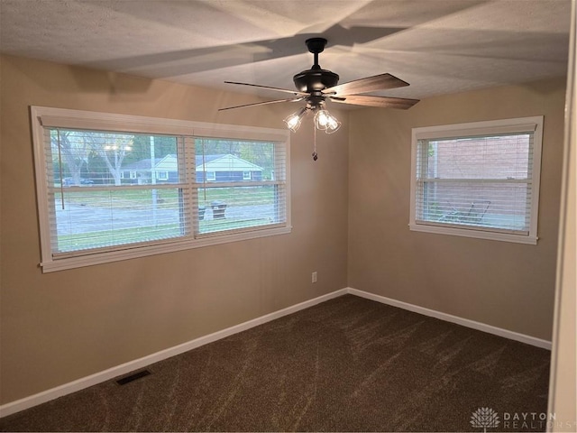 empty room with dark colored carpet and ceiling fan