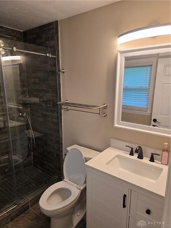 bathroom featuring a shower with door, vanity, and toilet