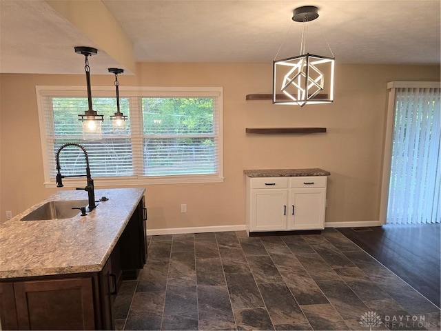 kitchen with stone counters, sink, dark wood-type flooring, hanging light fixtures, and white cabinets