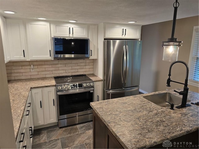 kitchen featuring white cabinetry, sink, light stone countertops, and appliances with stainless steel finishes