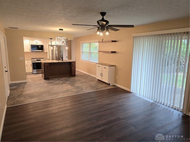 kitchen with pendant lighting, a center island, dark hardwood / wood-style flooring, white cabinetry, and stainless steel appliances