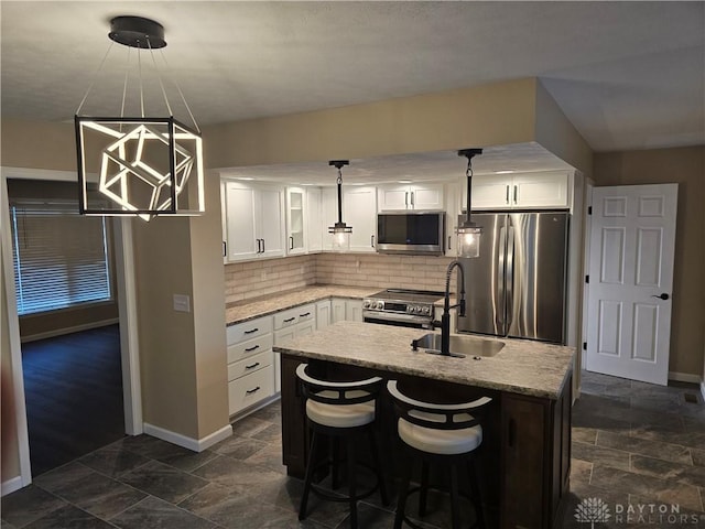 kitchen featuring a center island, sink, hanging light fixtures, white cabinetry, and stainless steel appliances