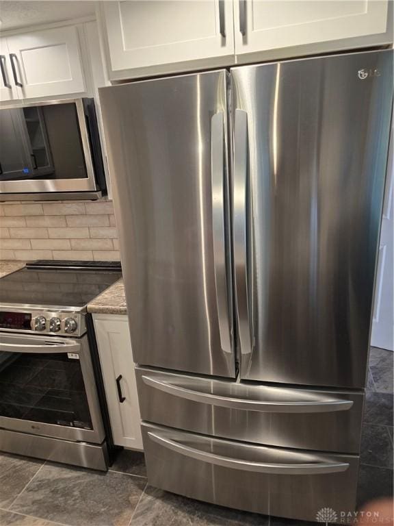 interior space with light stone counters, white cabinetry, and appliances with stainless steel finishes