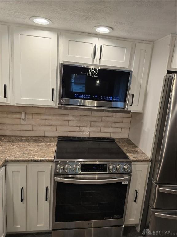 kitchen featuring light stone countertops, decorative backsplash, white cabinetry, and stainless steel appliances