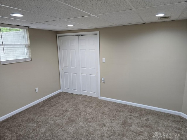 unfurnished bedroom with a drop ceiling, carpet floors, and a closet