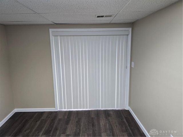 unfurnished room with dark hardwood / wood-style floors and a drop ceiling