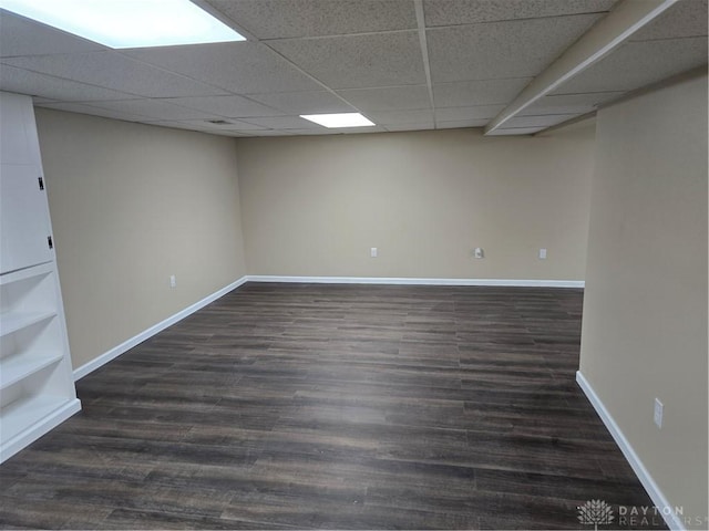 basement featuring a paneled ceiling and dark wood-type flooring