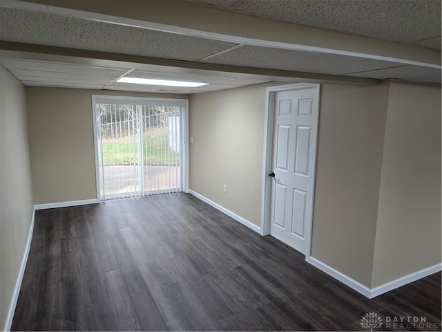 unfurnished room featuring beamed ceiling and dark hardwood / wood-style flooring