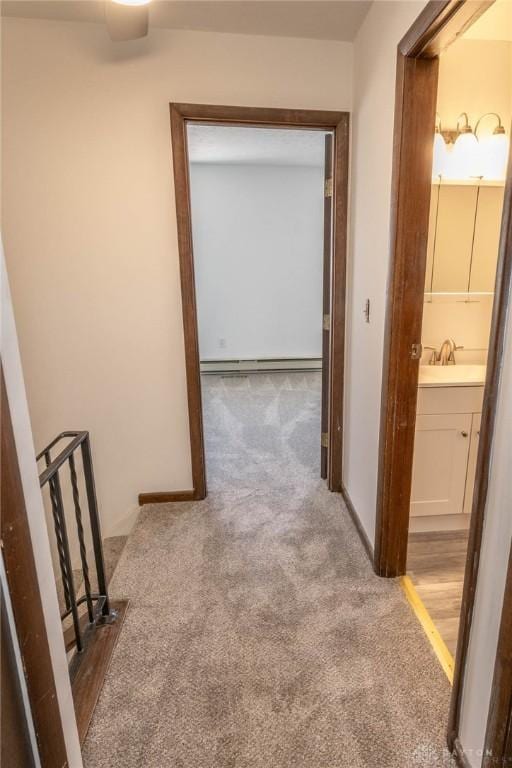 hallway featuring carpet flooring, sink, and a baseboard heating unit