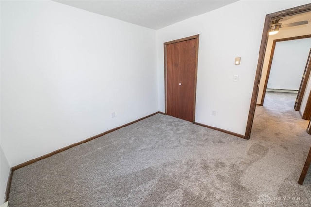 unfurnished bedroom featuring light carpet, a baseboard radiator, and a closet