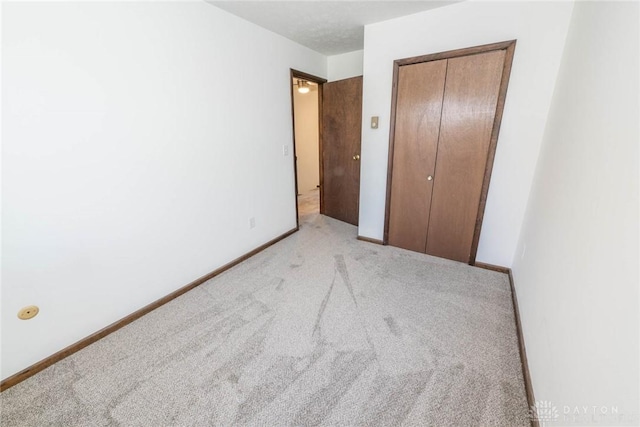 unfurnished bedroom with light colored carpet and a closet