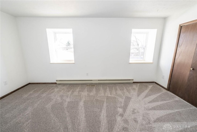 carpeted empty room featuring a baseboard radiator