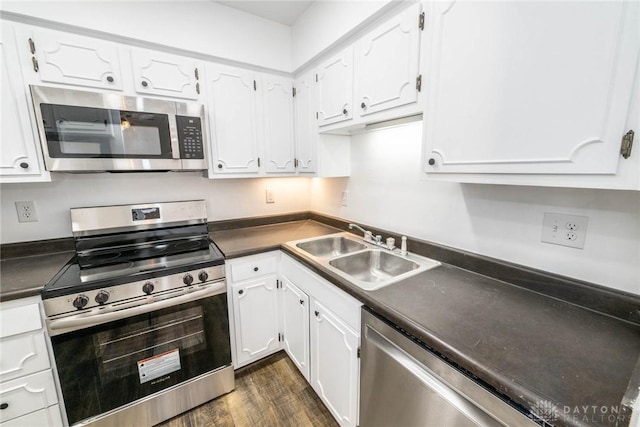 kitchen featuring white cabinets, appliances with stainless steel finishes, dark wood-type flooring, and sink