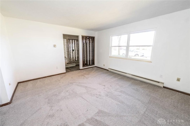 carpeted empty room featuring a baseboard radiator