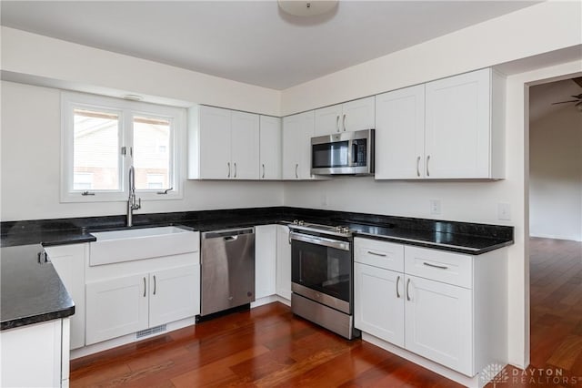 kitchen with white cabinetry, sink, dark wood-type flooring, and appliances with stainless steel finishes