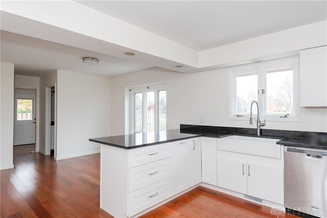 kitchen with kitchen peninsula, white cabinetry, stainless steel dishwasher, and plenty of natural light