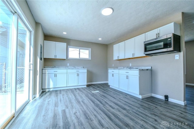 kitchen featuring hardwood / wood-style floors, a textured ceiling, and white cabinets