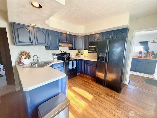 kitchen featuring blue cabinetry, sink, kitchen peninsula, light hardwood / wood-style floors, and black appliances