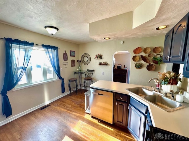 kitchen featuring dishwasher, light wood-type flooring, a textured ceiling, and sink