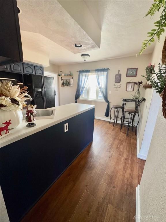 kitchen featuring black fridge with ice dispenser and dark wood-type flooring