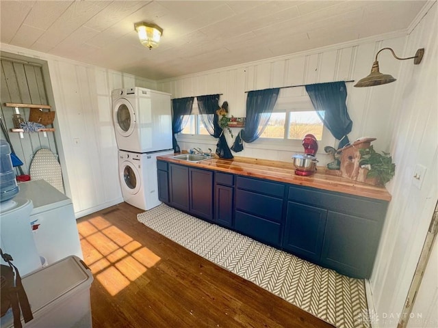 laundry room featuring sink, light wood-type flooring, and stacked washer / dryer