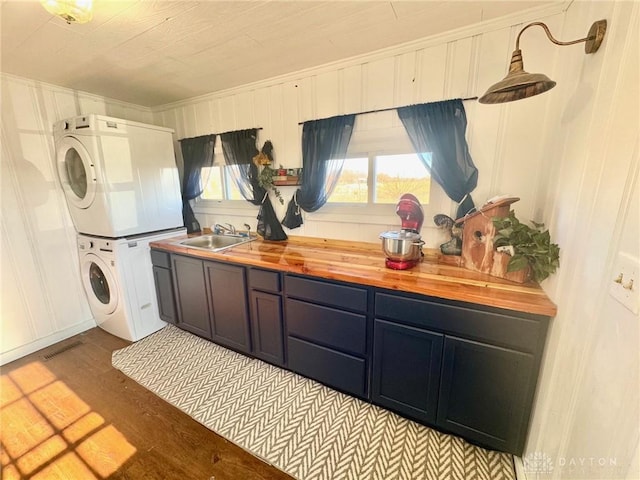 clothes washing area with stacked washer / dryer, sink, and light hardwood / wood-style floors