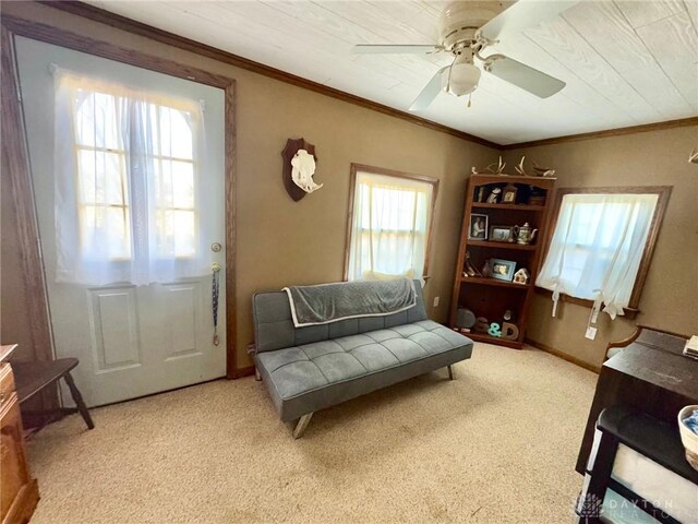 living area featuring ceiling fan, crown molding, and light colored carpet