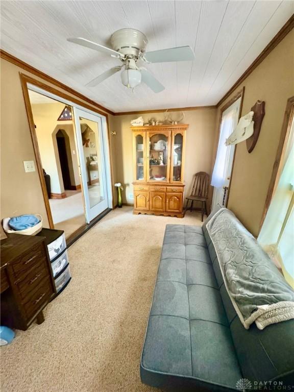 interior space with ornamental molding, carpet floors, ceiling fan, and french doors