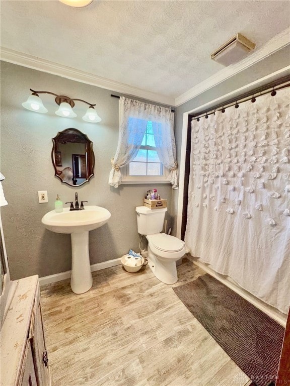 bathroom featuring hardwood / wood-style flooring, ornamental molding, walk in shower, toilet, and a textured ceiling