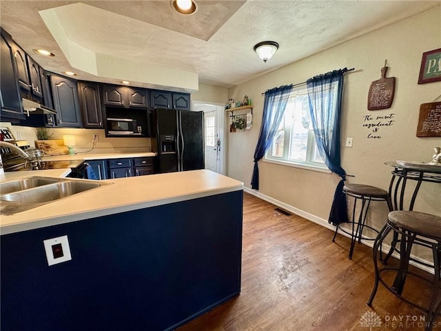 kitchen with dark hardwood / wood-style floors, black appliances, sink, kitchen peninsula, and a textured ceiling