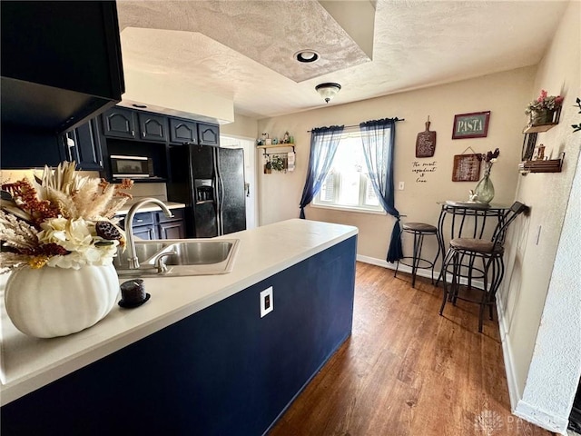 kitchen featuring blue cabinets, sink, wood-type flooring, a textured ceiling, and black appliances