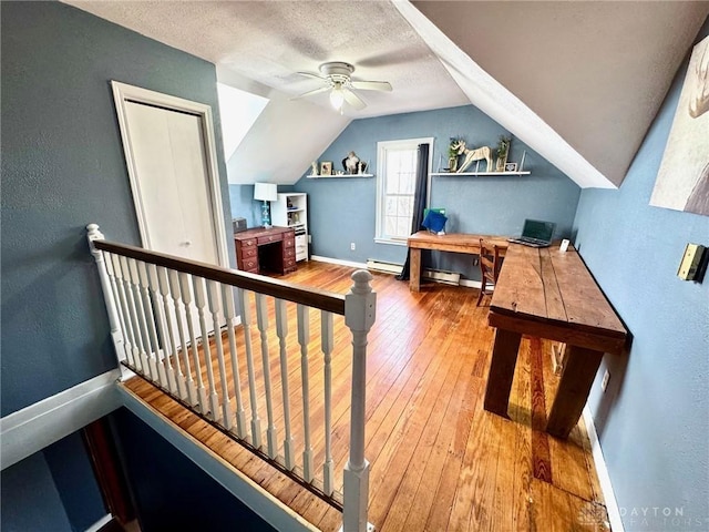 bonus room featuring vaulted ceiling, hardwood / wood-style floors, a baseboard radiator, ceiling fan, and a textured ceiling