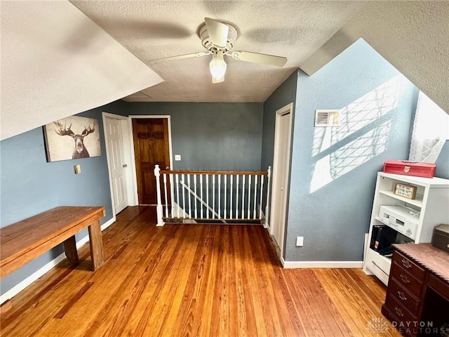 additional living space with ceiling fan, light hardwood / wood-style floors, and a textured ceiling